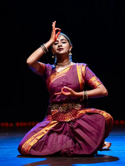 A seated pose from a solo performance, with the dancer's hands forming a mudra above her head. This posture signifies meditation and inner focus.