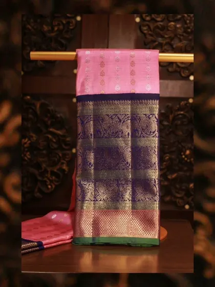 An enchanting pink Kanjivaram with a contrasting blue border featuring peacock and elephant motifs in gold zari.