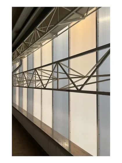 A detail from an industrial project site, showing the translucent polycarbonate wall panels and exposed steel truss work. This image highlights our interest in the honest expression of industrial materials and structural systems.