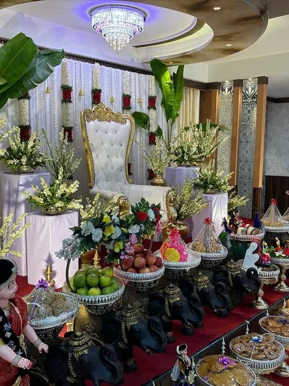 A stage with a white curtain backdrop, red rose accents, and large banana plants.