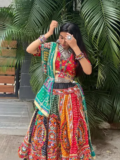 A multi-colored chaniya choli with a black skirt base and a green bandhani dupatta. The silver jewelry adds a perfect contrast.