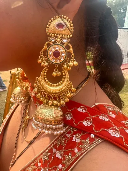Another angle of the multi-tiered gold jhumkas, showing their intricate design and length.