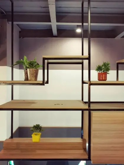 A close-up of the custom-designed suspended shelving, showing how plants are integrated into the structure to bring life and greenery to the office environment.