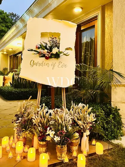 A beautiful welcome sign for the 'Garden of Eve' themed party, surrounded by a bed of candles and rustic floral arrangements.