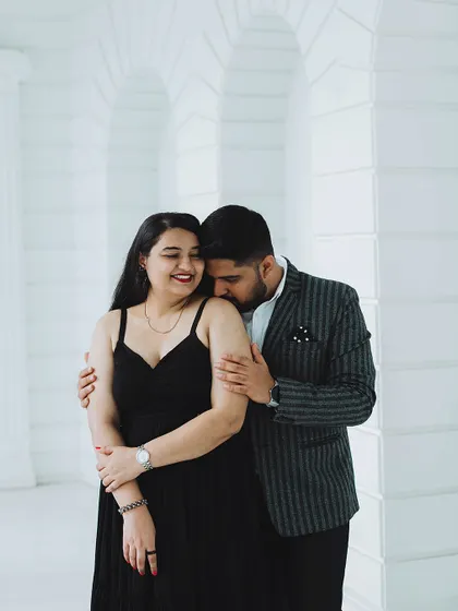 A romantic pre-wedding photo where the groom-to-be gently kisses his partner's shoulder in a tender embrace.