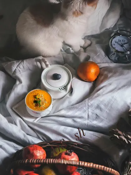 A cozy flatlay scene with a fruit basket, a teapot, and my cat peeking in. This lifestyle shot feels personal and authentic, capturing a quiet, comfortable moment at home.