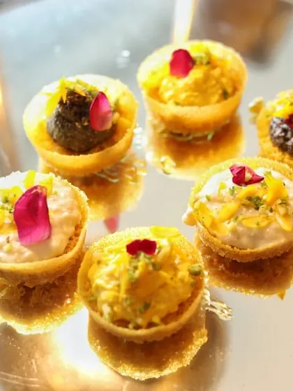 These bite-sized tartlets are filled with a variety of sweet creams and garnished with delicate rose petals. Served on a mirrored tray, their reflections create a beautiful and abundant display.