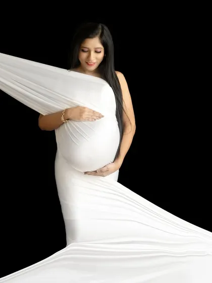 A classic fine-art drape shot against a solid black background. The focus is entirely on the form and the beautiful wrapping of the fabric.
