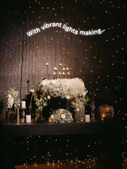 A decor detail from the 'Starry Sangeet', featuring a cascade of baby's breath and candles set against a wall of twinkling fairy lights, adding to the magical, celestial atmosphere.