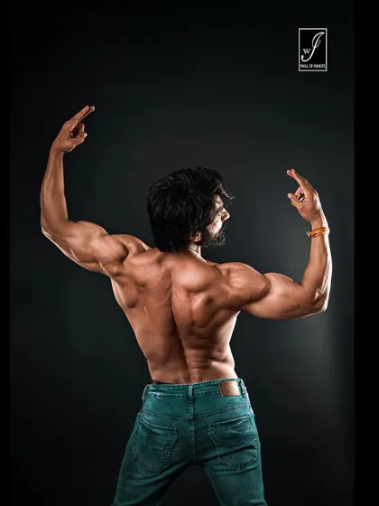 A wide back shot showcasing the full expanse of the latissimus dorsi muscles. My lighting setup is specifically designed to create deep shadows and bright highlights, revealing every detail of back development.