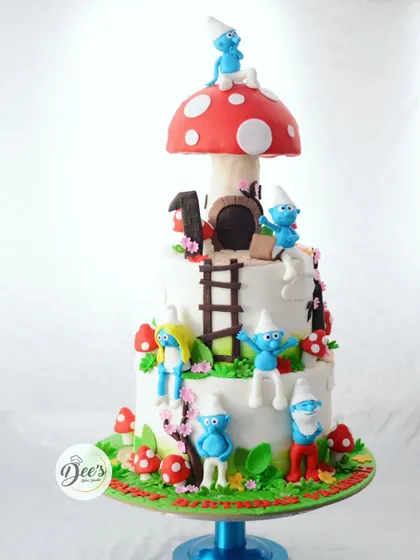 Welcome to the Smurf village. This multi-tiered cake is a playful scene with hand-sculpted Smurf characters, a giant mushroom house, and lots of fun details for a memorable first birthday.