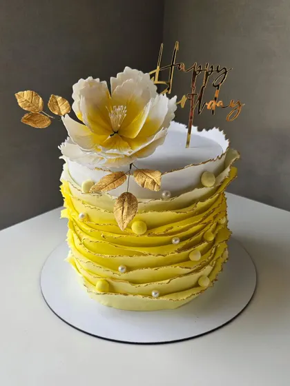 A beautiful yellow ruffle cake with a handmade sugar peony on top. The ombre effect and delicate ruffles make this a stunning piece.