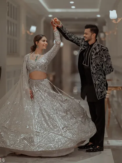 A beautiful shot of the couple twirling in a grand corridor, the bride's silver lehenga catching the light perfectly.