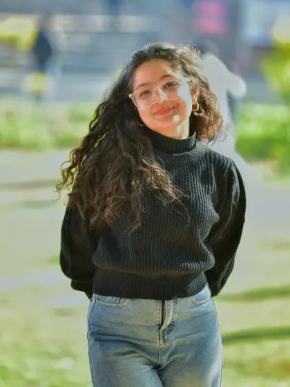 A relaxed and happy portrait with a soft, sunny background. Her gentle smile and casual pose make this a very approachable and warm lifestyle shot.