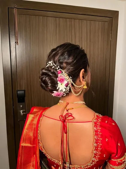 The intricate bridal bun adorned with fresh flowers and a traditional hair accessory. The hairstyle is a key element of the classic Marathi bridal look.