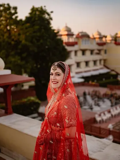 A happy, smiling portrait of the bride on the palace balcony. Her joy is infectious, and the magnificent venue in the background tells the story of a grand destination wedding.