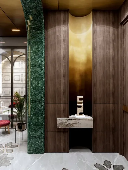 A dramatic entryway featuring a curved wall with rich green marble and wood paneling. A custom brass inlay and floral marble floor pattern create a luxurious and unforgettable first impression.