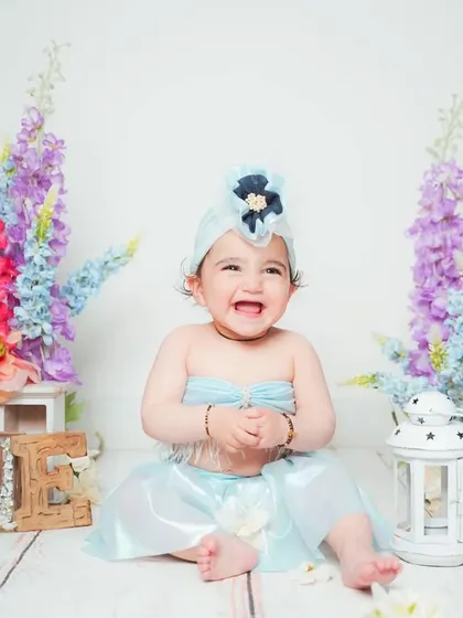A joyful baby clapping her hands during her first birthday photoshoot.