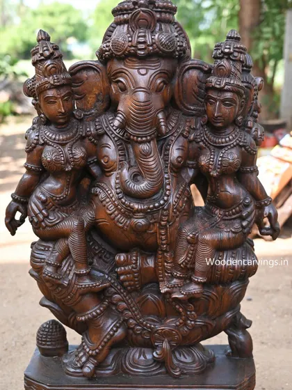 A close-up of Ganesha with his consorts Buddhi and Siddhi, focusing on the central deity.