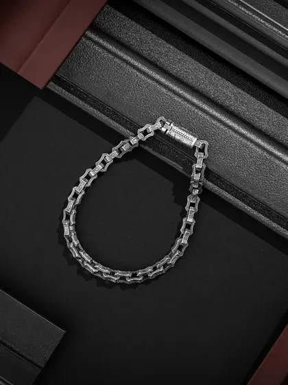 A minimalist yet powerful shot of a men's bracelet from Orionz Jewels. The composition uses contrasting brown and black textured panels to frame the product, creating a visually interesting and masculine look.