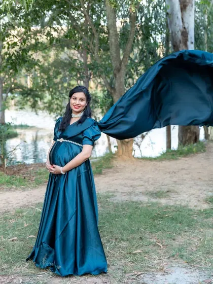 A dramatic outdoor shot with a flowing teal satin gown against a lakeside backdrop.