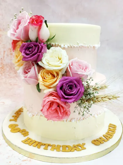 This two-tiered floral fault line cake is the epitome of modern elegance. A cascade of fresh roses in shades of pink, purple, and cream appears to burst through the delicate pink and ivory tiers, creating a design that is both dramatic and romantic.