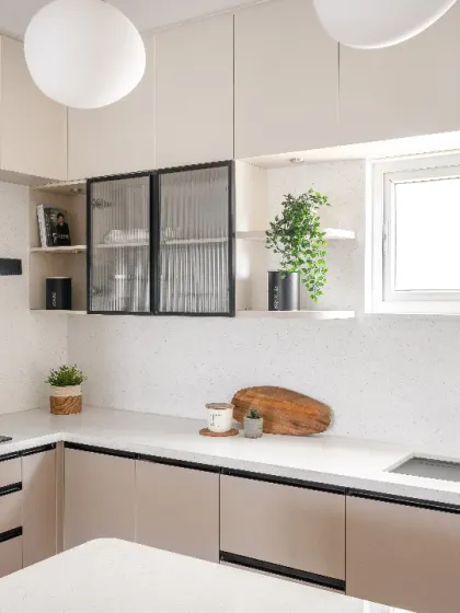 A bright and functional kitchen from the Rohan Upavan project. The design features light-toned quartz countertops, ample storage, and glass-front cabinets to keep the space feeling open and airy.