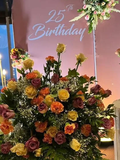 A detailed shot of the stunning floral arrangement from the 25th birthday party, showcasing a mix of colorful roses and baby's breath.