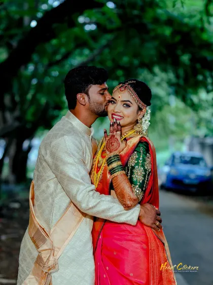 A candid and happy moment between a couple in traditional wedding attire. The groom's playful kiss on the cheek brings out the bride's beautiful smile.