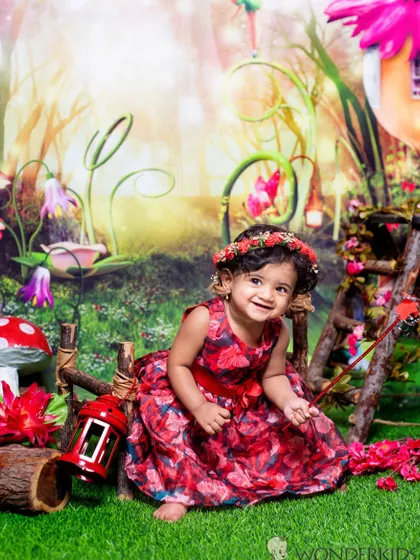 A happy little girl in a red floral dress, exploring a magical forest setting. The vibrant colors and whimsical props create a beautiful and imaginative portrait.