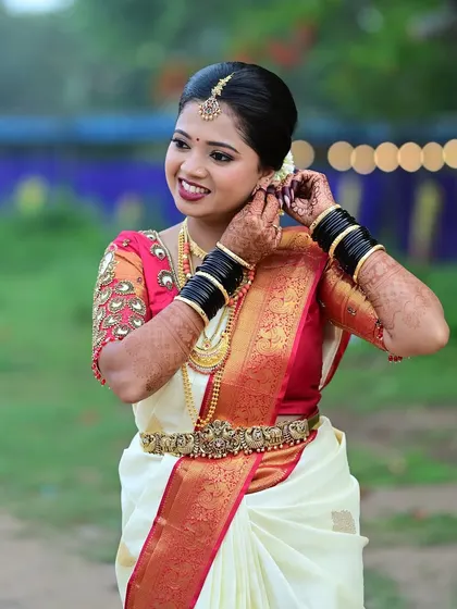 A candid shot of the bride adjusting her earring. This shows the practical, long-lasting nature of the makeup and hair.