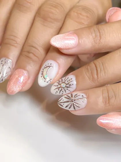 A full view of the celestial-themed nail art, with a sun, moon, and stars over a shimmery cat eye base.