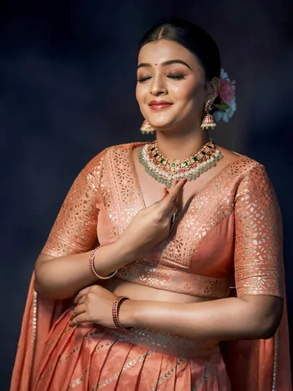 A serene moment captured during a photoshoot, highlighting the soft color and delicate fabric of the peach lehenga.