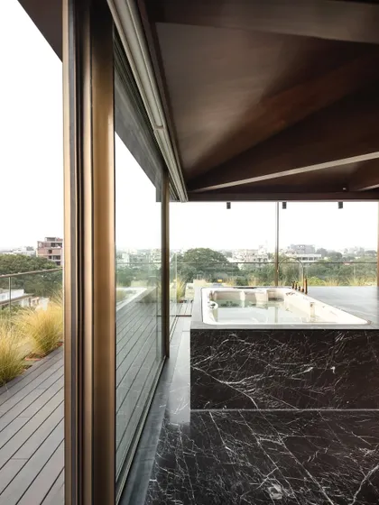 A jacuzzi on the upper terrace, encased in black marble, opens up to the sky and the city beyond. It creates a luxurious, open-air bathing experience that connects with the urban environment.