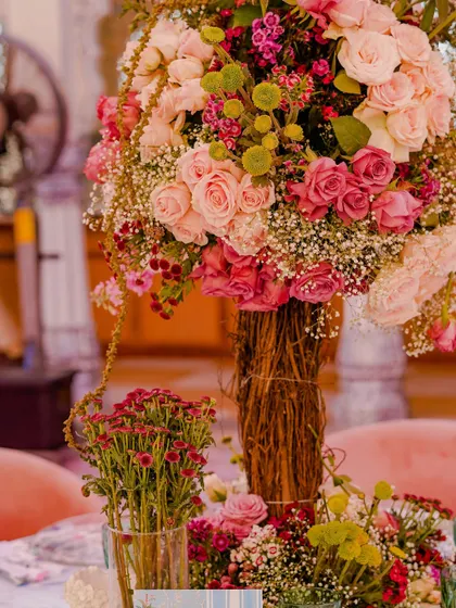 A lush floral centerpiece featuring a mix of pink roses and baby's breath. The natural, slightly rustic arrangement adds to the romantic garden feel.