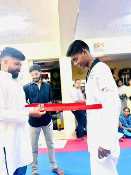 This young man proudly receives his red belt after years of training.