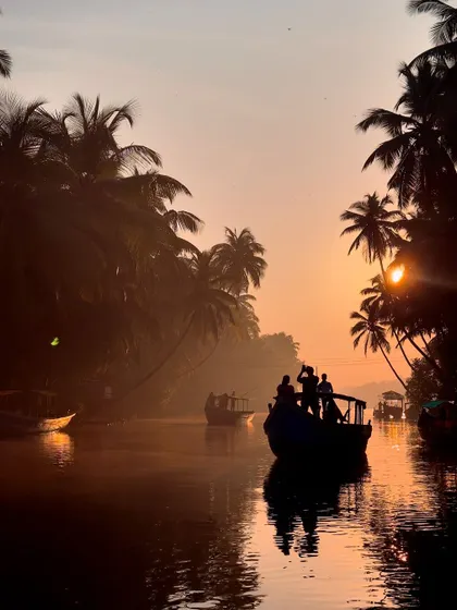 A silhouette of a boat and people against the beautiful sunset in Honnavar.