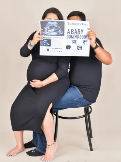 I love incorporating fun and personal ideas into a shoot. Here, the couple uses a custom newspaper prop to announce their "coming soon" arrival, making for a playful and memorable portrait.