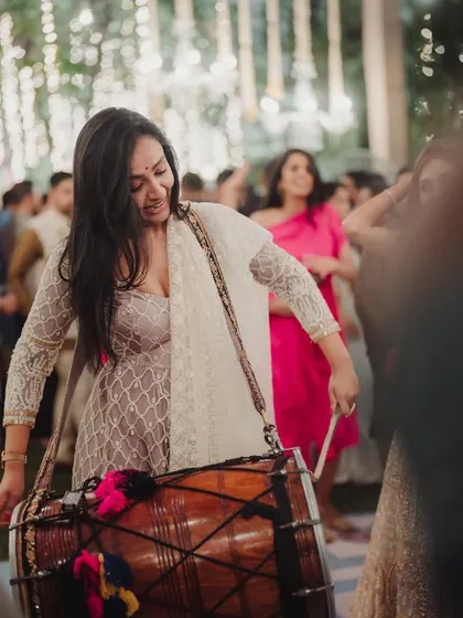 A guest playing the dhol, adding to the high energy and festive atmosphere of a Mehendi party.