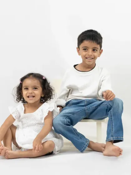 A mother and her children share a playful, loving moment against a clean, white background. This minimalist style allows their genuine emotions to be the focus of the photograph.