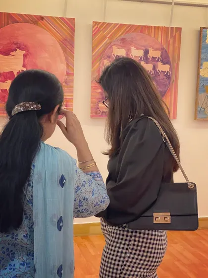 Visitors at the gallery viewing my "Kamaduha" series. Art is about connection, and I love seeing people engage with the stories and themes in my paintings.