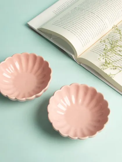 Two pink, flower-shaped ceramic bowls styled with an open book, creating a peaceful and charming lifestyle scene.