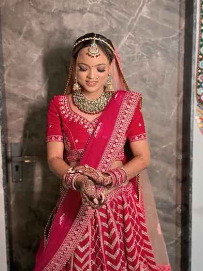 My beautiful bride Mittal, ready for her wedding. She is wearing a traditional red lehenga, and we've paired it with classic makeup featuring a bold red bindi.