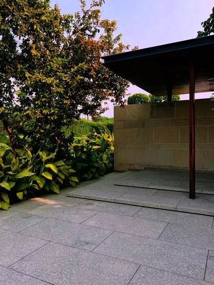 This shot captures the interplay of light and shadow under a covered walkway. The surrounding greenery creates a cool and inviting atmosphere.