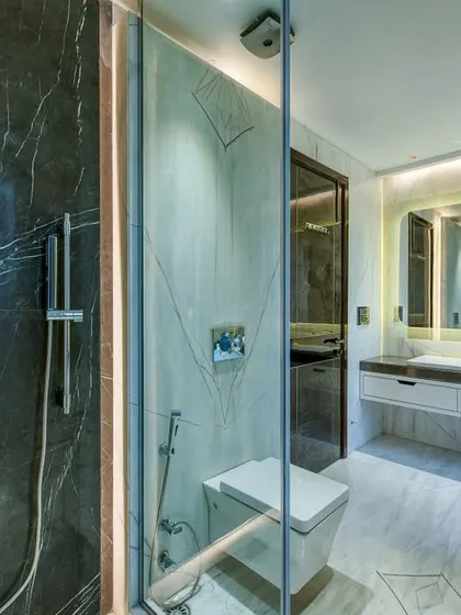A master bathroom concept featuring a mix of dark and light marble. The glass-enclosed shower with a modern digital control panel adds a high-tech touch.