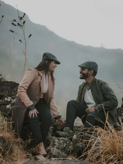 A candid moment of conversation and laughter, set against the rustic beauty of a stone wall during their vintage-style pre-wedding shoot.