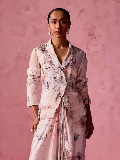An abstract print blazer paired with a draped skirt. This look combines sharp tailoring with soft draping, creating a unique and artistic silhouette that is sure to turn heads.