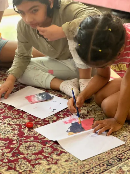 Kids working together to paint their popsicle sticks. This is the first step in creating their very own decorative wall hanging.