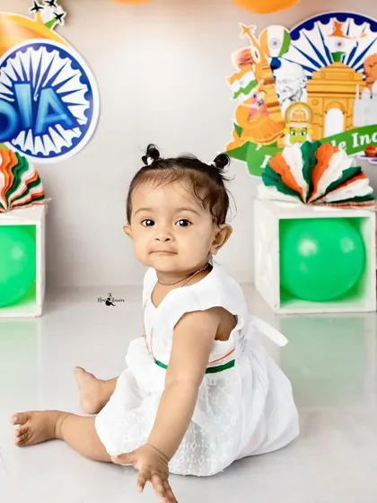 A sitting pose from the Independence Day session, with the baby girl looking adorable in her white dress with a tricolor belt.