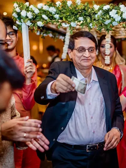A guest joyfully throws money during the bridal procession, a traditional gesture to bless the bride and ward off evil.